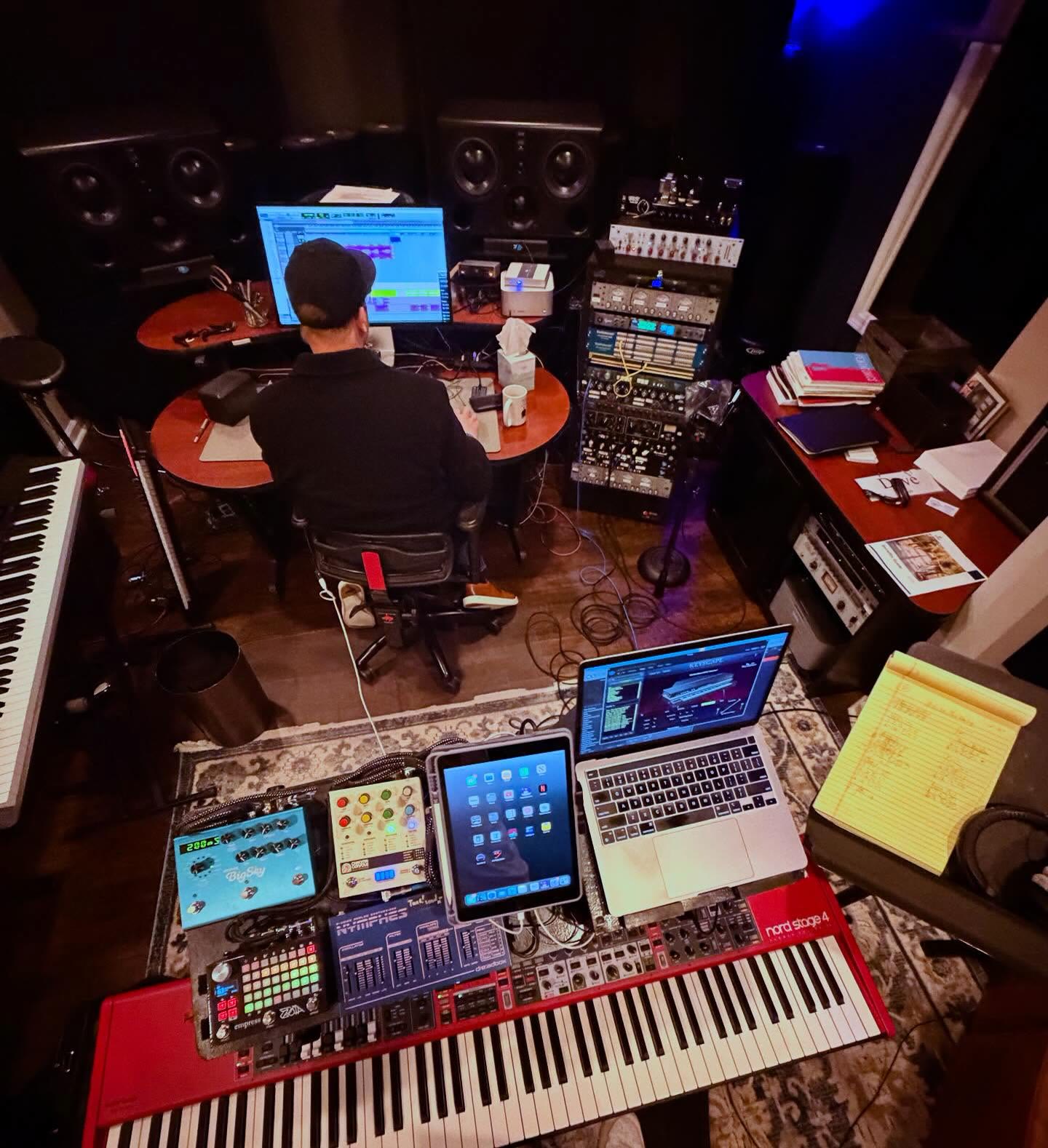Dave Tough working at a studio computer surrounded by instruments and recording gear